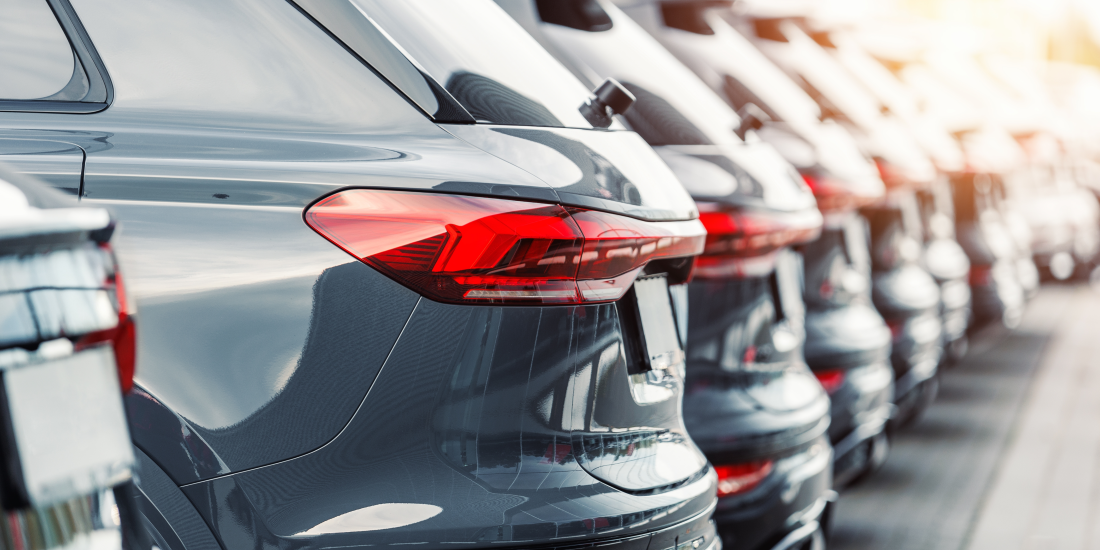 Heckansicht mehrerer Autos, die in einer Reihe auf einem Parkplatz stehen, symbolisch für steigende Kosten im KFZ-Bereich.